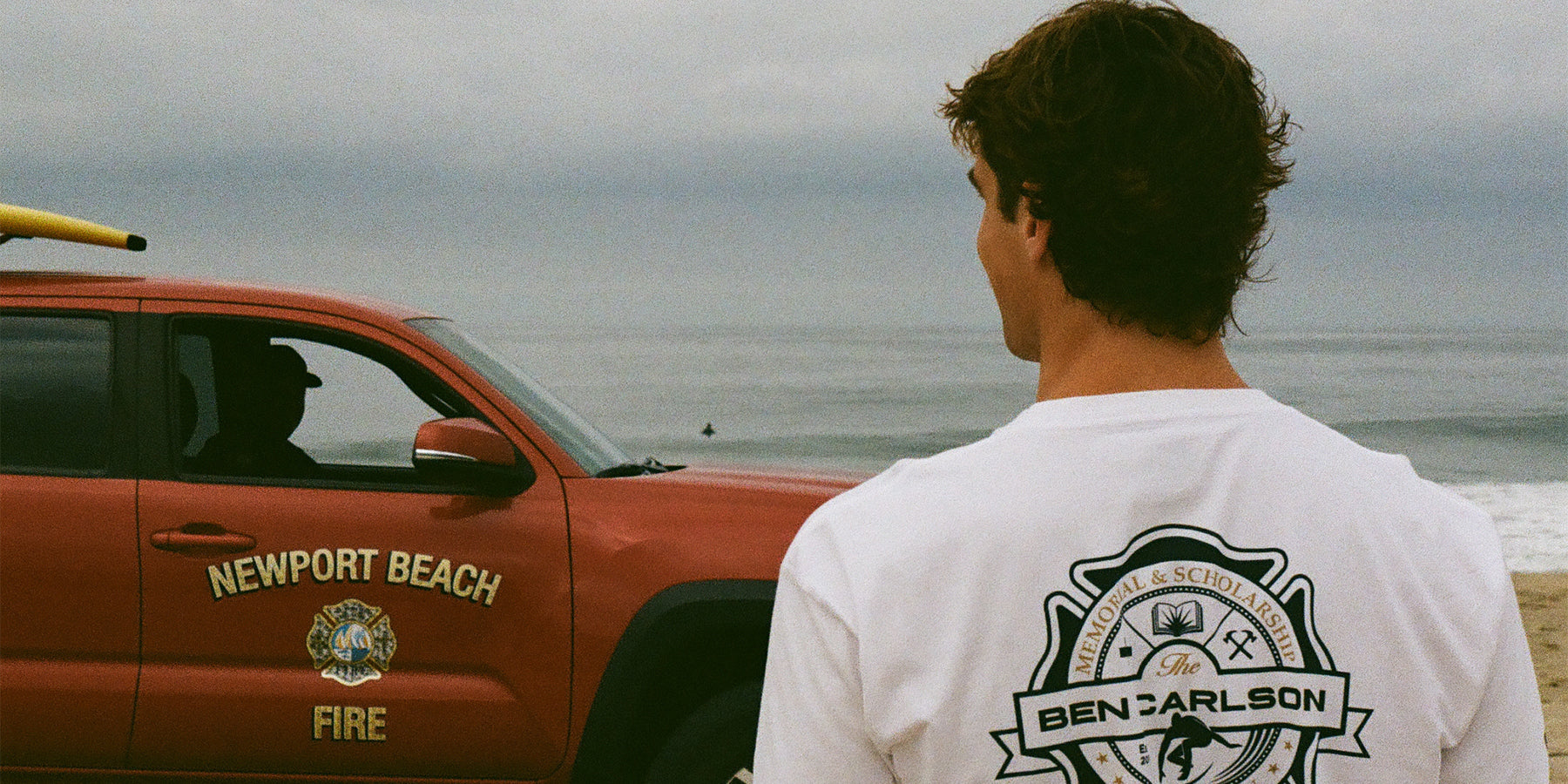 Ben Carlson standing in front of a red truck owned by the Newport Beach Lifeguards.