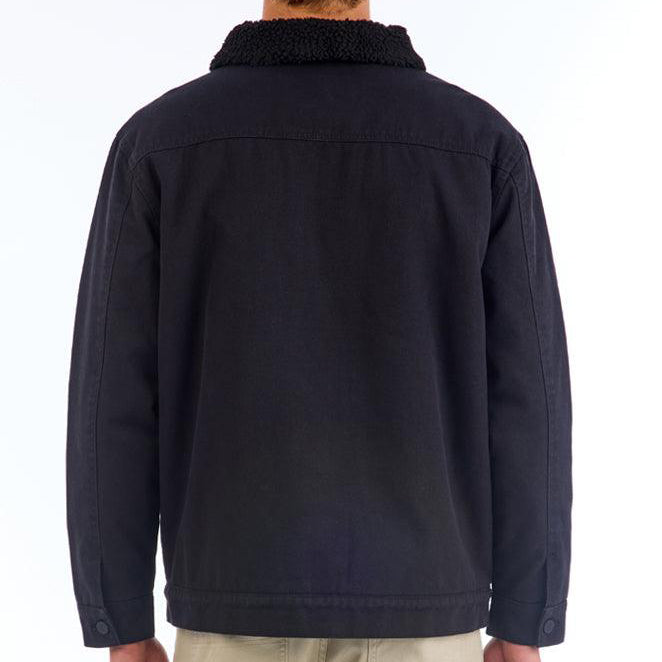 Front view of a black long sleeve heavyweight cotton button up jacket. It has a thick, cotton-lined collar with two patch flap pockets on each side of the chest. Above the left pocket is a white circular patch.