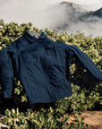 IPD jacket displayed outdoors on a bush with a scenic mountain background