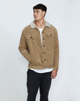 The front view of a man wearing a brown corduroy jacket with his right hand in the right pocket at the waist.