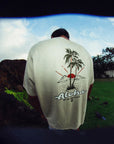 Man wearing white haze short sleeve tee with large Hawaiian themed print and word Aloha on the back.