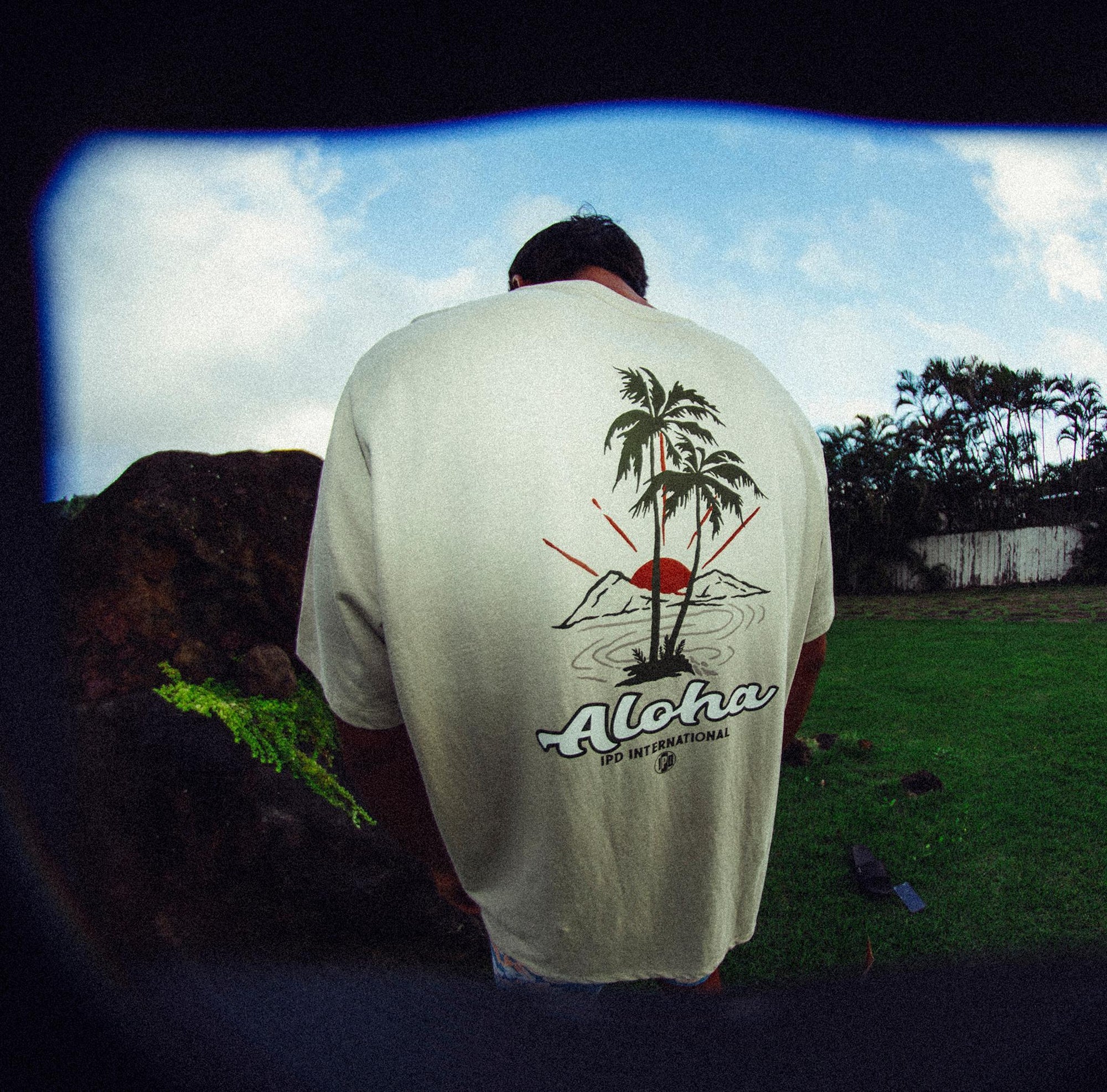 Front view of white haze short sleeve tee with small palm trees and word Aloha printed over the heart.