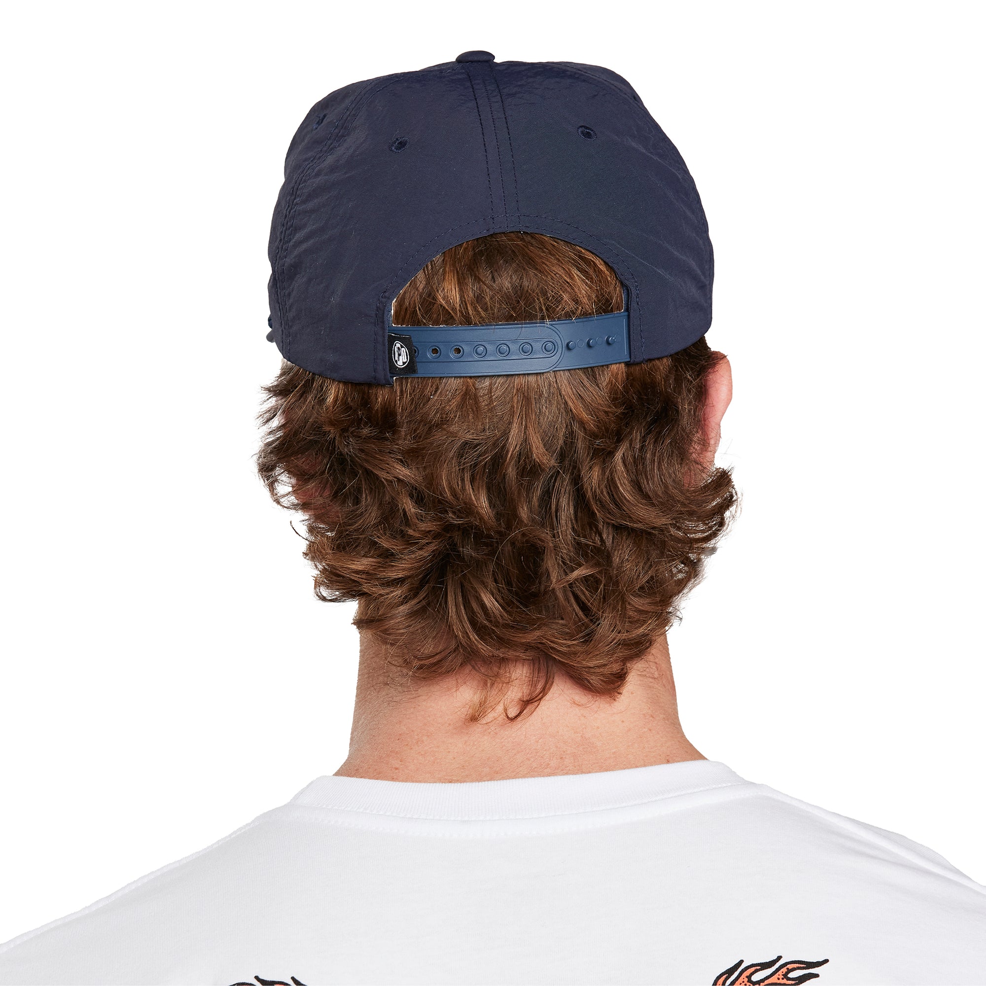 A young man wearing an Atlas navy hat, back view, displaying the adjustable strap and the back design of the hat.