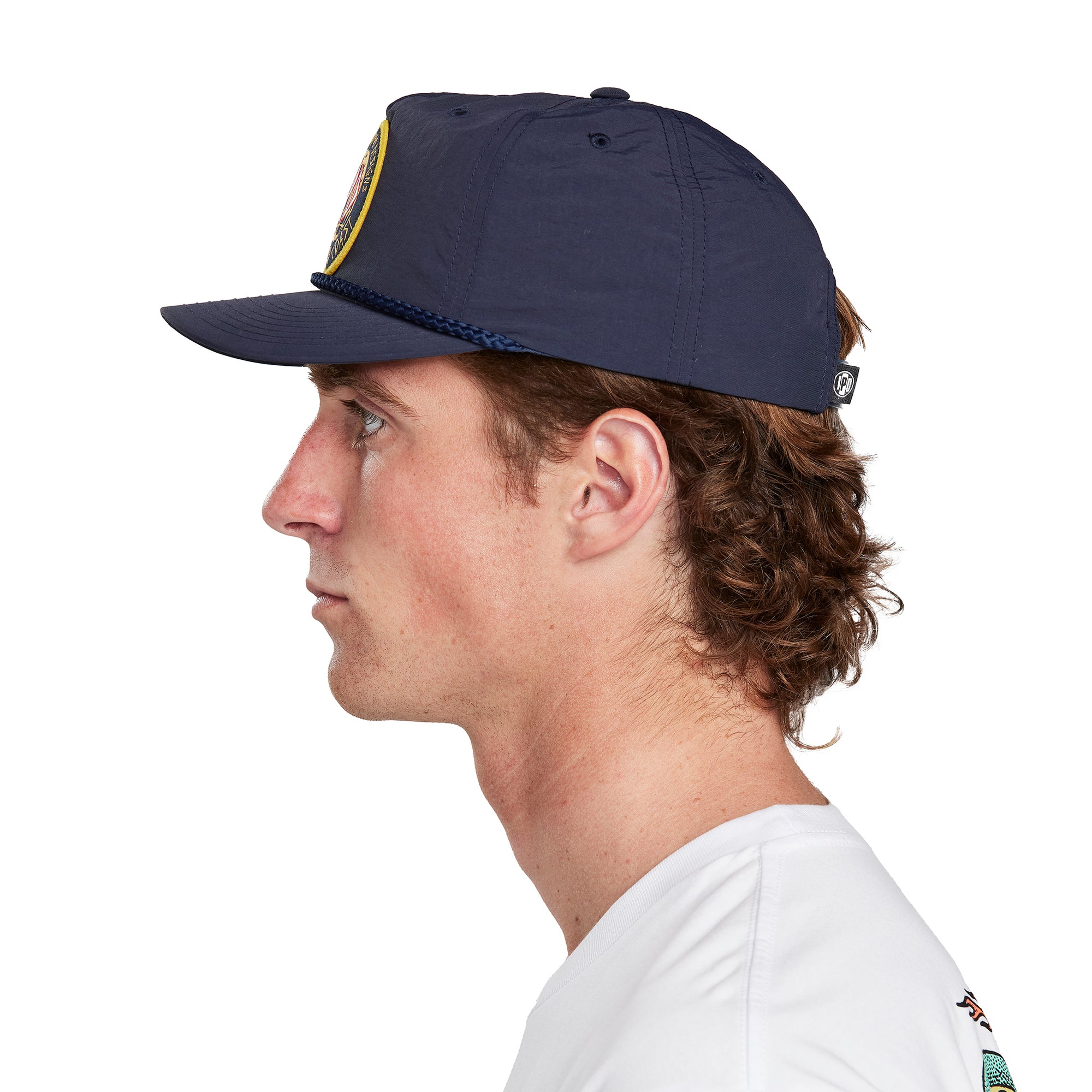 A young man wearing an Atlas navy hat, side view, illustrating the side profile and design of the hat.