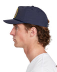 A young man wearing an Atlas navy hat, side view, illustrating the side profile and design of the hat.