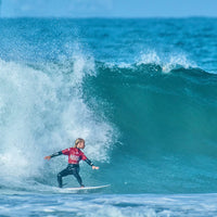 brett showing great form while exiting the barrel of a wave on his surfboard