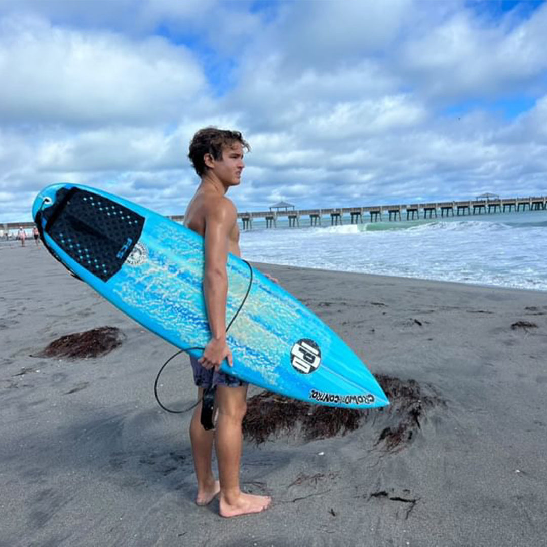 campbell standing out on the beach, holding his surfboard and scoping out the waves