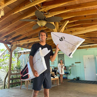 chase showing off a broken surfboard with the nose in one hand and the rest of the board under his arm