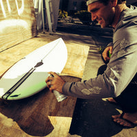 dane looking excited while he sprays some wax on his shortboard