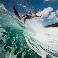 ola riding the lip of a breaking wave with hands in the air