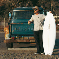 kolty living the dream, leaning on the back of his old chevy truck with surfboard in hand 