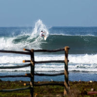 leon hammering a frontside snap off the lip of a wave, spraying water in the air and looking stylish