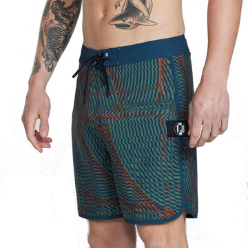 Front side view of navy blue and olive green abstract striped boardshorts with blends of red and an I P D logo on the side.