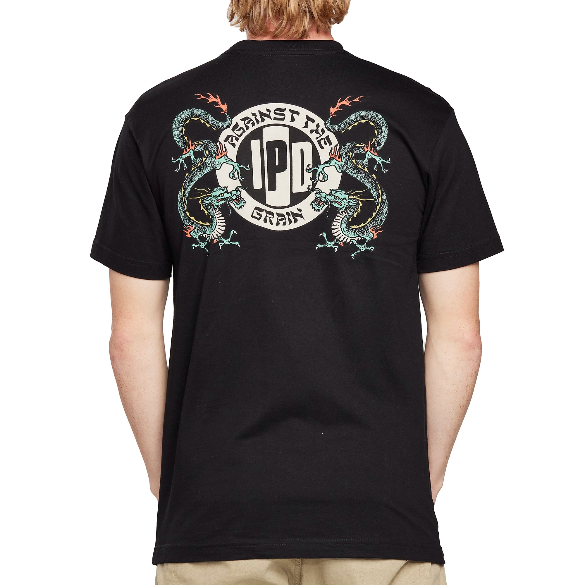 Back view of a white short sleeve tee with a large I P D logo with the words Against the arching above, the word Grain arching below, and two green dragons on each side of the logo.