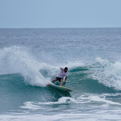 nick coming off a nice frontside turn off the lip of a wave, spraying water and showing great form on the surfboard