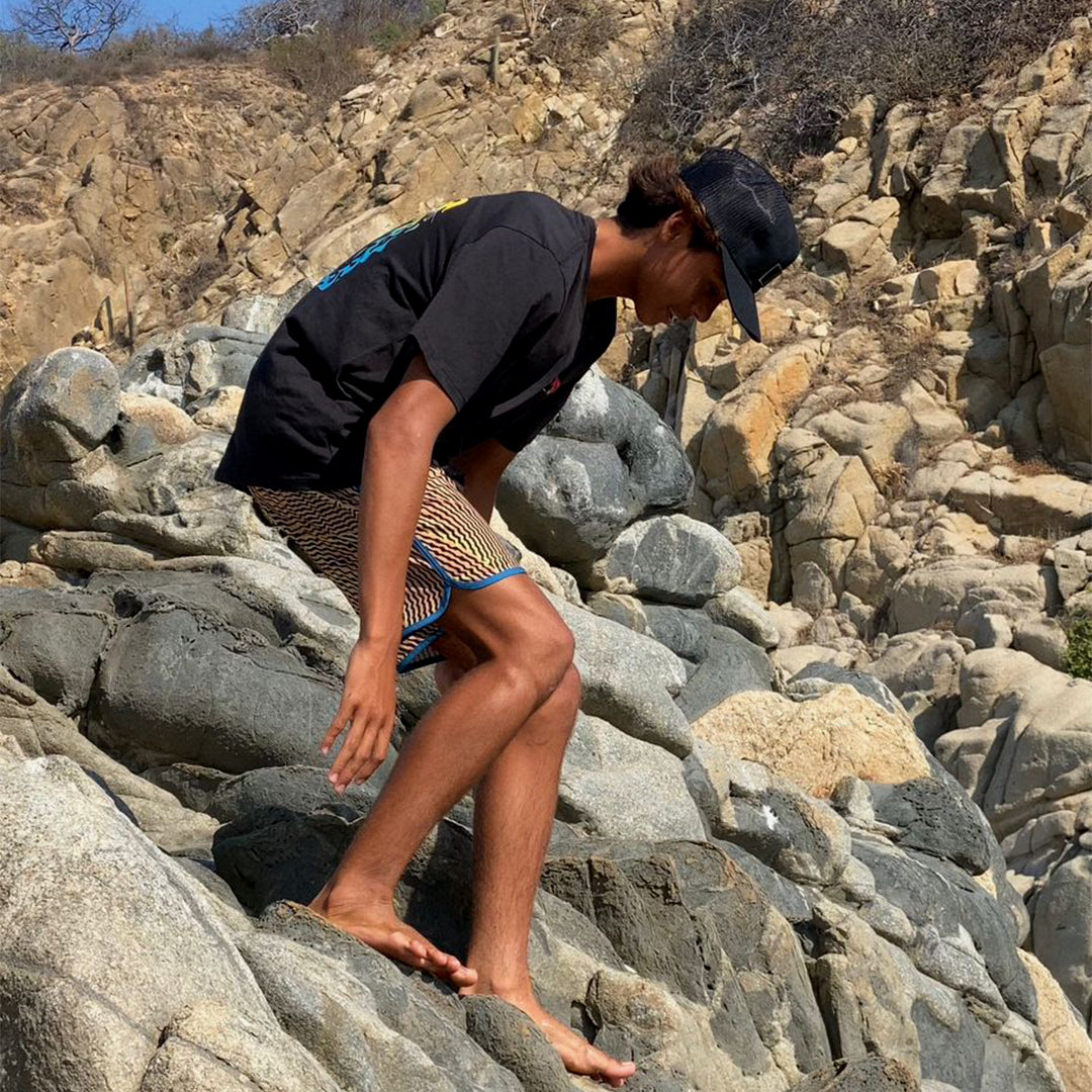 nesher carefully climbing over some rocks near a cliff wall