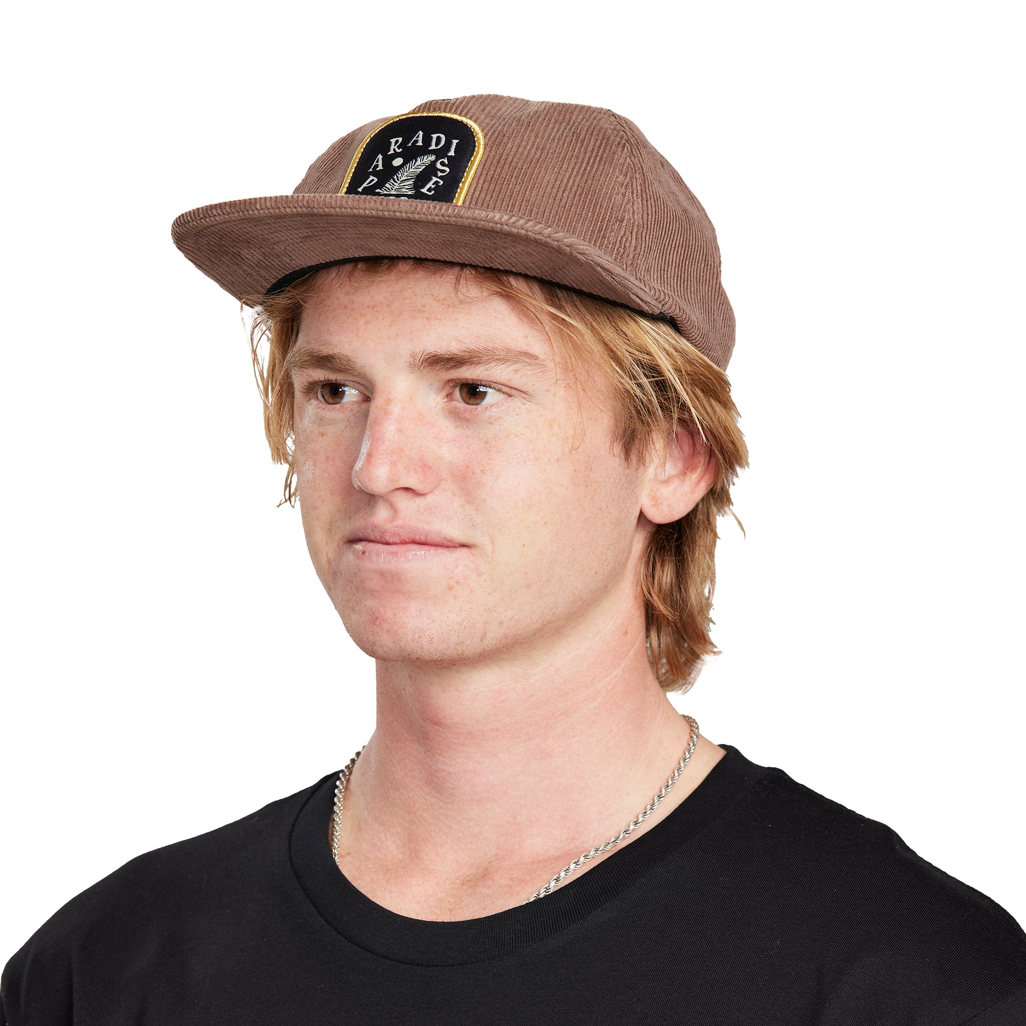 A young man wearing a Paradise brown hat, front view, clearly showing the logo and front design of the hat.