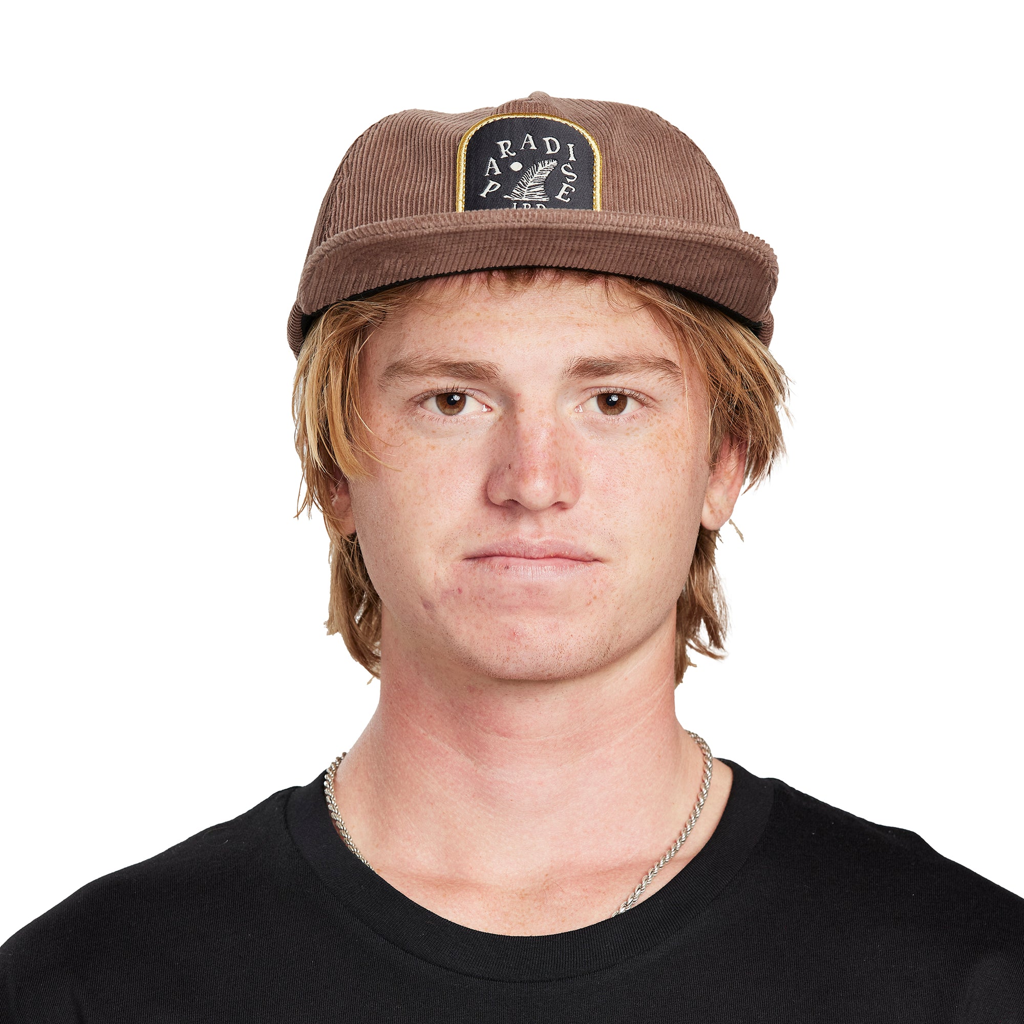 A young man wearing a Paradise brown hat, angled front view, showing the logo on the front of the hat.