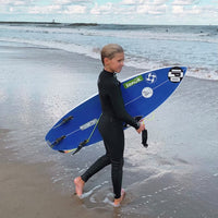 reed stepping into the water, donned in a wetsuit, carrying his surfboard and gearing up to ride the waves