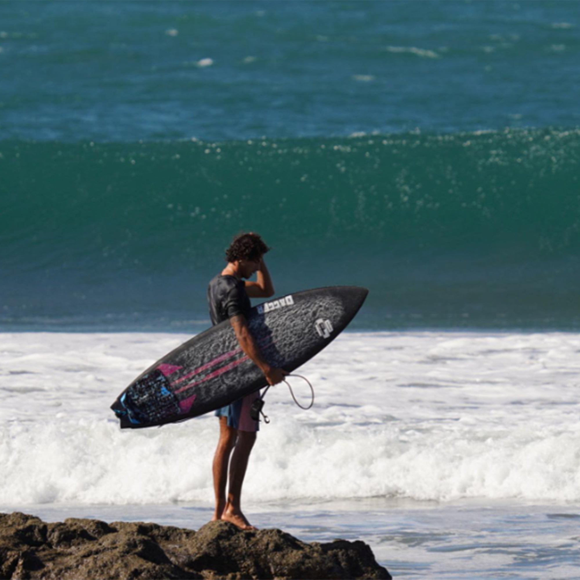 francisco standing on a rock with board in hand checking out the waves