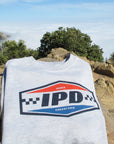 IPD logo sweatshirt displayed on rocks with a scenic background.