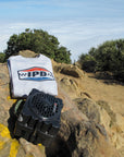 IPD logo sweatshirt and Turtlebox speaker displayed on rocky terrain with a scenic view.