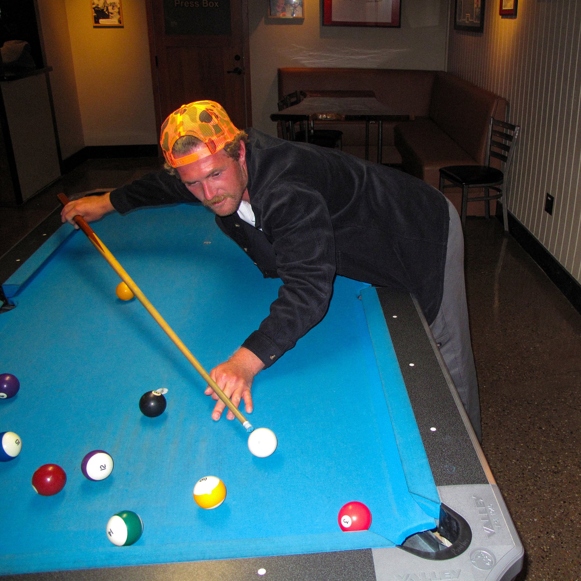 Man playing pool wearing the IPD Pierside corduroy shirt in black.