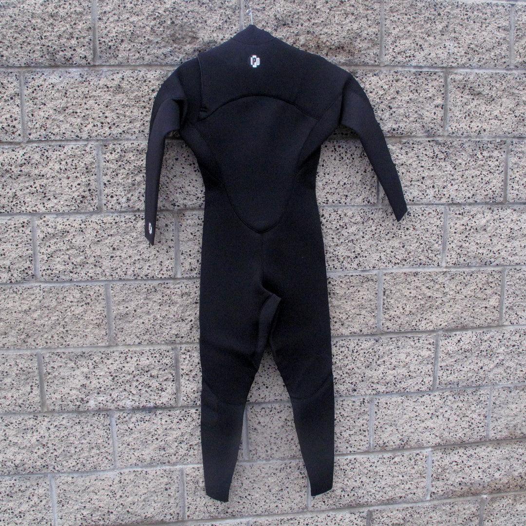 Back side of mens wetsuit hanging on wall. Full body with I P D circle logo at the base of neck. 