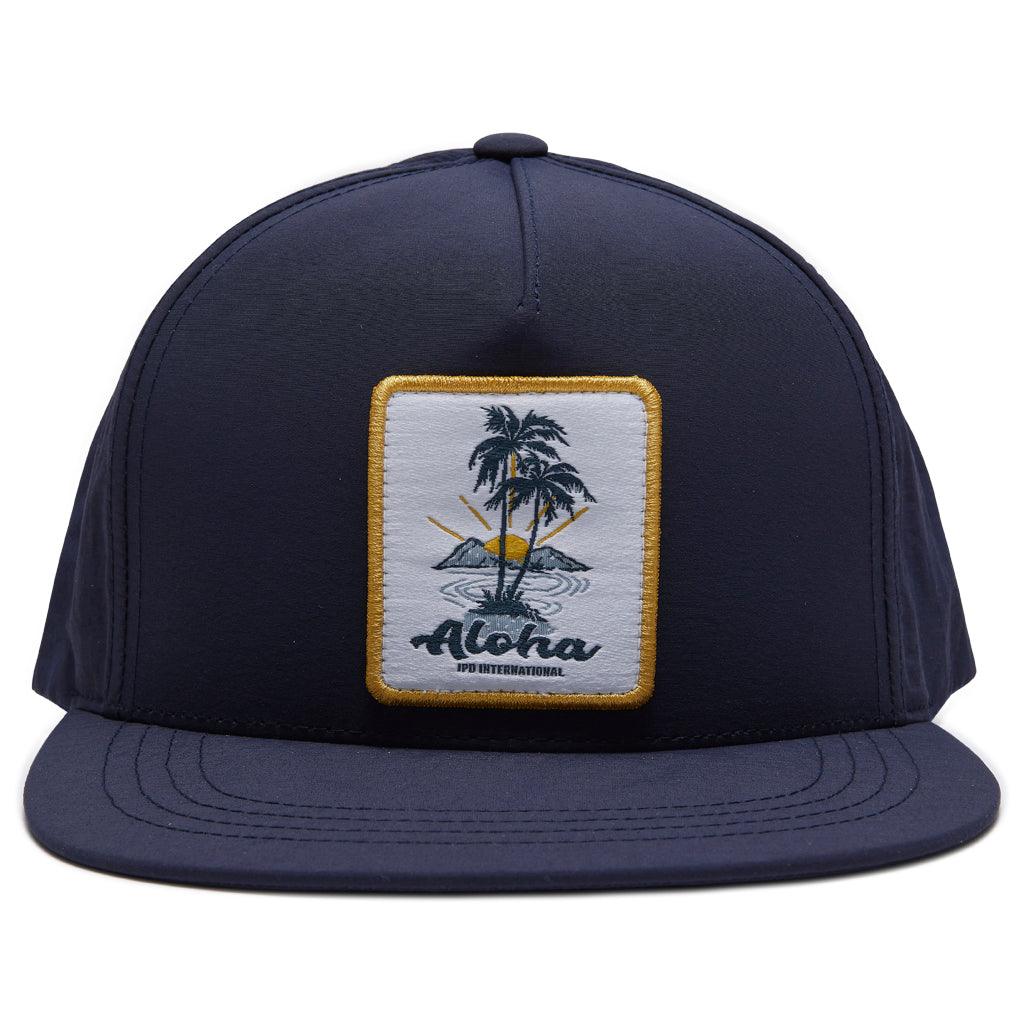 aloha snapback in navy. Patch on front panel with aloha logo with aloha in navy in front of two palm trees and yellow border 