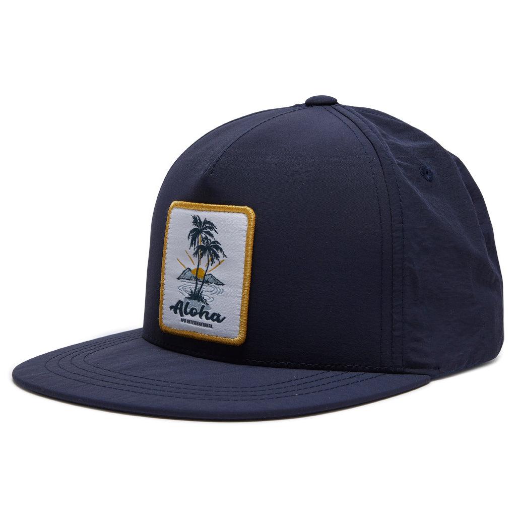 side view of aloha snapback in navy. Showing side panel and front patch with aloha in navy blue in front of two palm trees