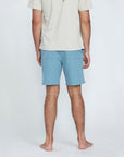 The back view of a man wearing blue shorts with a pocket on the right side. 