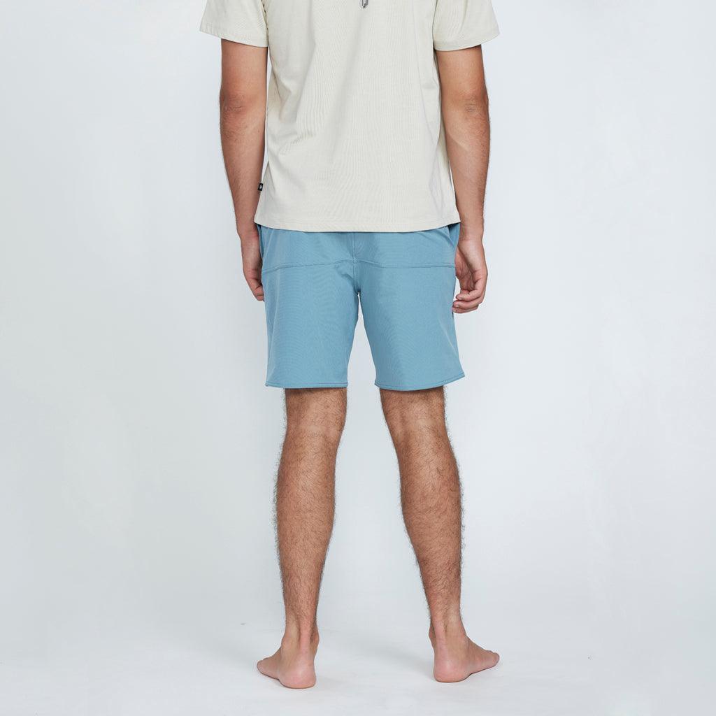 The back view of a man wearing blue shorts with a pocket on the right side. 