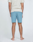 The back view of a man wearing blue shorts with a pocket on the right side.