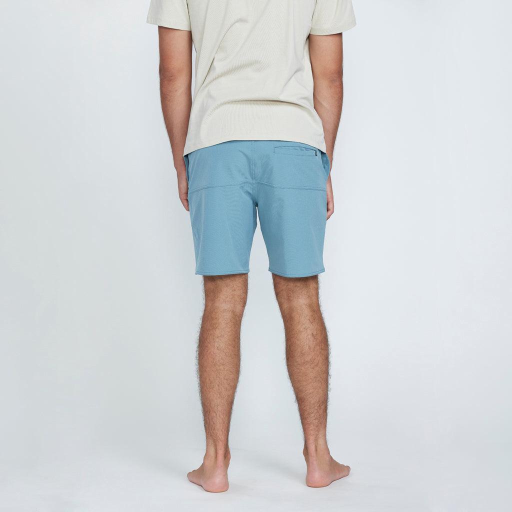 The back view of a man wearing blue shorts with a pocket on the right side.