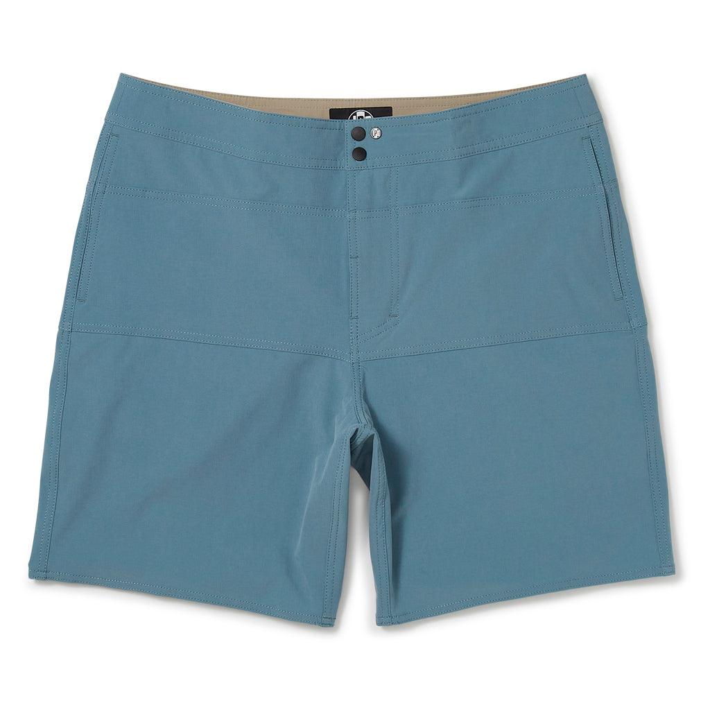 The front view of blue shorts with two side pockets, two metal snaps at the closure, and a small circular I P D logo to the left of the snaps. The waistband has two double rows of stitching. There is also double stitching along the edges of a horizontal rectangular section located below the waist, above the crotch and extending to the left and right side seams. 