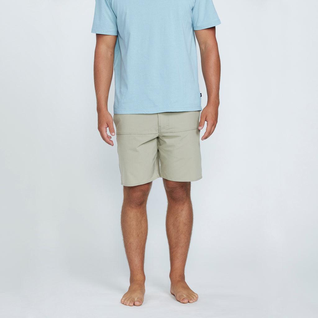 The front view of a man wearing tan shorts with two side pockets.