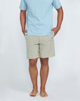 The front view of a man wearing blue shorts with two side pockets with his hands in the pockets. 