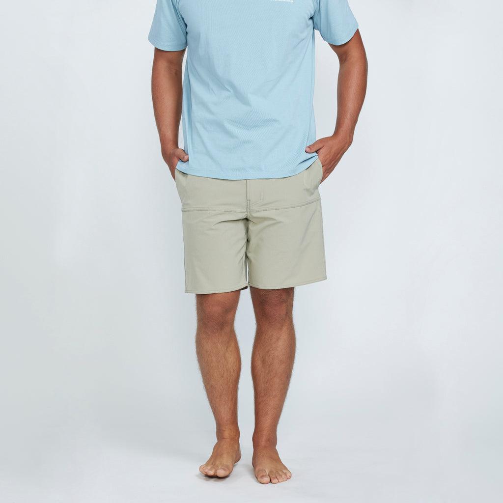 The front view of a man wearing blue shorts with two side pockets with his hands in the pockets. 