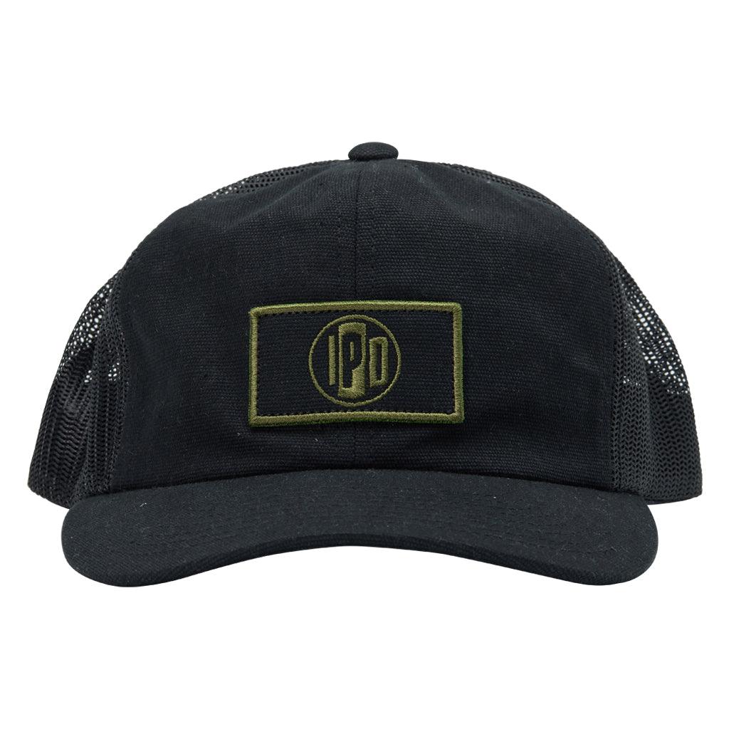 The 1697 Trucker Snapback features a lower profile trucker styling in the color black with a black mesh back. It features a brown and black rectangular front patch with the I P D logo in the center.
