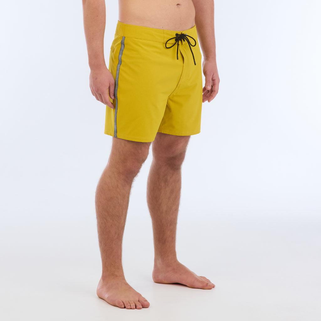 The B100 Chase boardshort features a 16” length and solid yellow coloring with a black and white striped side taping. It also has a waistband tie, side zipper pocket, and a black IPD logo patch halfway up the left leg taping. 