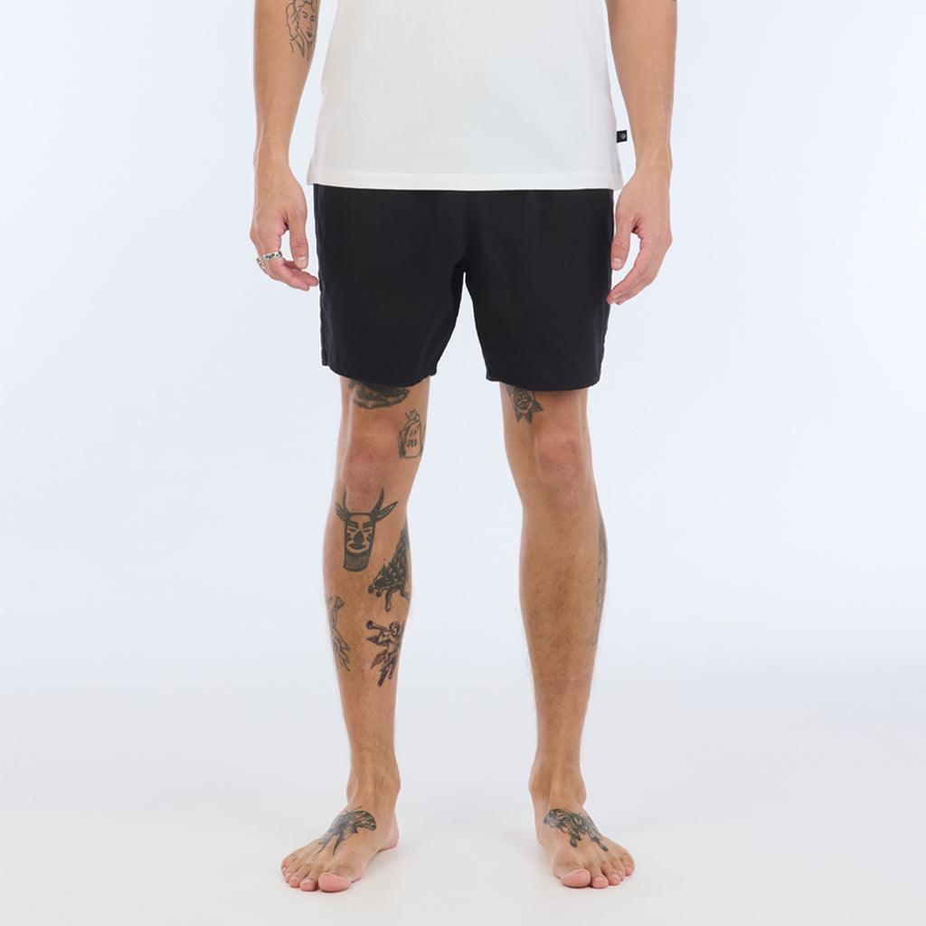 on model with white top:The Foundation Walkshort is a classic walkshort silhouette that comes in at a 17” length. It features a solid black coloring, and features an elastic waistband and drawcord. The pocketing is two side pockets and two back patch pockets. It features the signature smaller IPD flag label on the lower left leg.