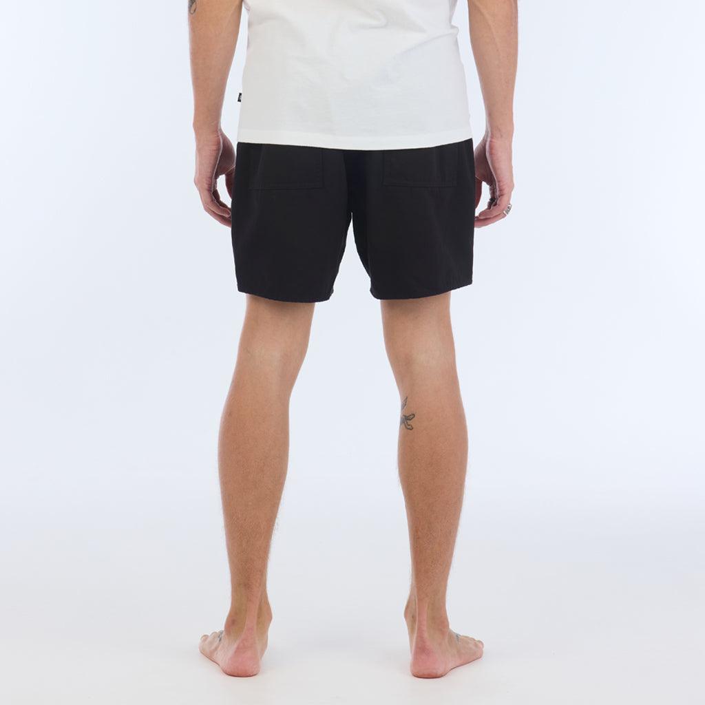 on model, back view:The Foundation Walkshort is a classic walkshort silhouette that comes in at a 17” length. It features a solid black coloring, and features an elastic waistband and drawcord. The pocketing is two side pockets and two back patch pockets. It features the signature smaller IPD flag label on the lower left leg.
