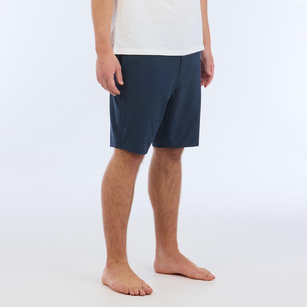 The Carter Hybrid features a 19” length in a classic walkshort silhouette in a waterproof fabric. The base color of the short is a heathered navy. The short also features belt loops, a zipper and button closure, two side pockets and two back pockets, and the signature smaller IPD flag label on the lower left leg.