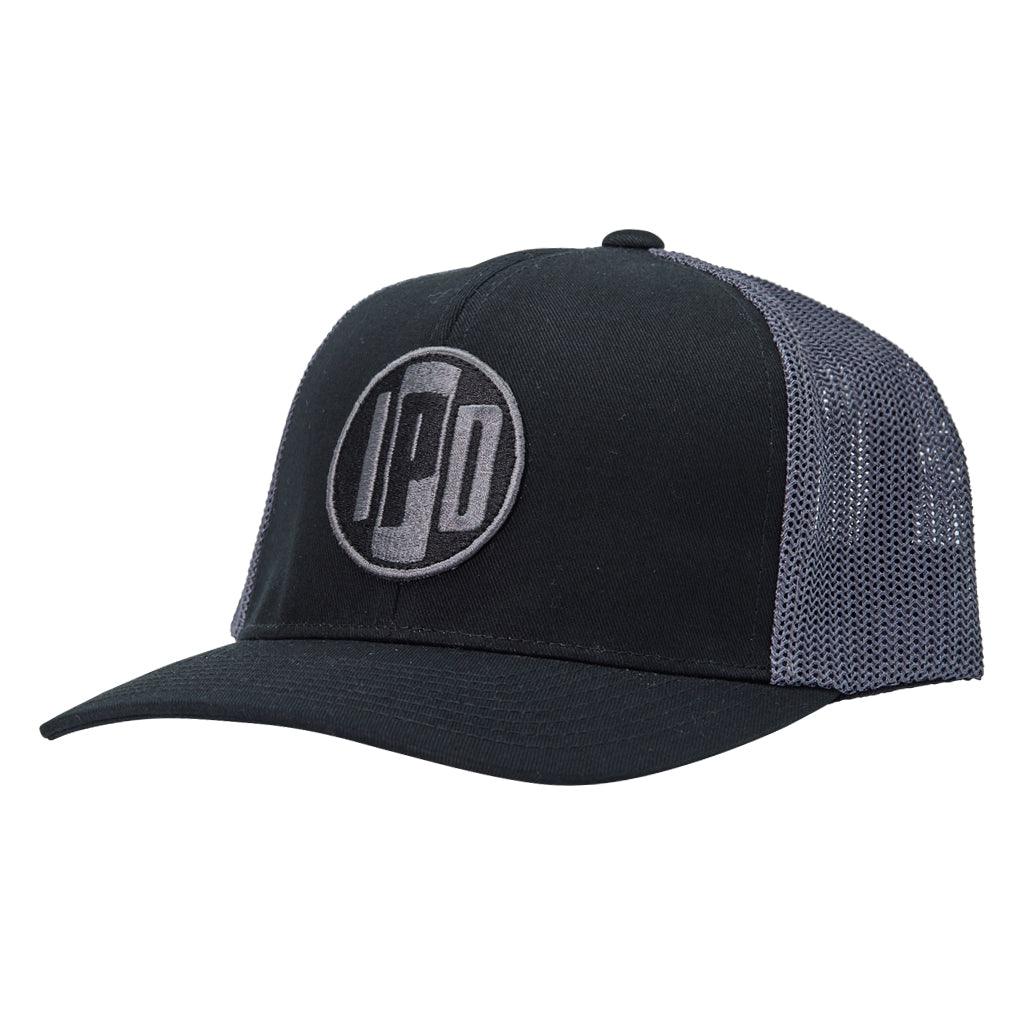 side view:A structured trucker hat with dark grey mesh on the back and a cotton twill black front. In the middle of the front is an embroidered IPD black and dark grey patch logo. This hat has a curved brim and adjustable snap back.