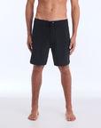 The HI 83 Solid Scallop boardshort on male model features an 18” length and an all black coloring, delivering maximum comfort in a minimalist look. It also has a waistband tie, back patch pocket, and a black IPD logo patch halfway up the left leg taping